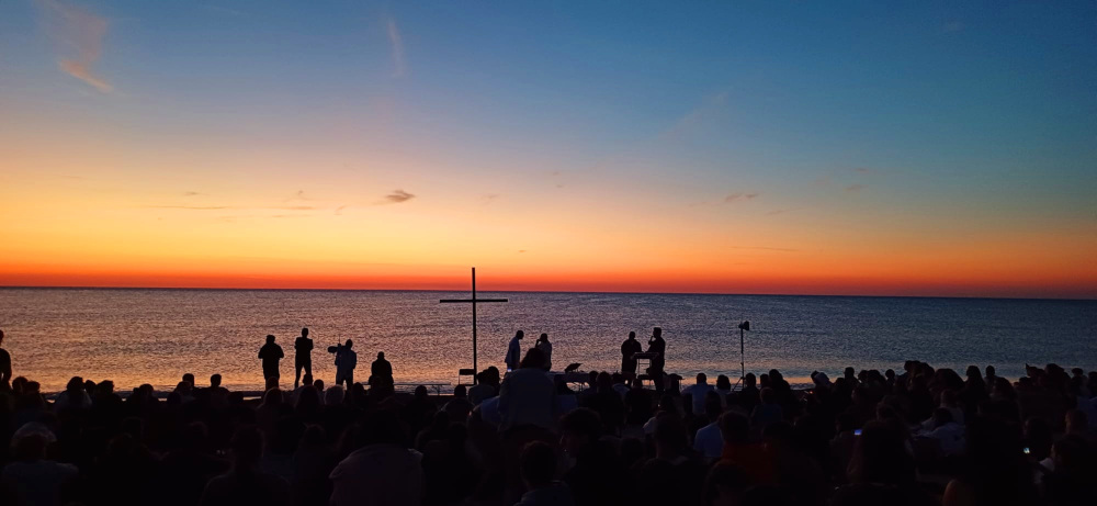 Una folla di giovani in riva al mare con il vescovo Palmieri